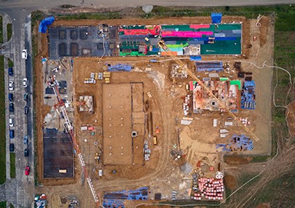 Aerial view of construction site with building materials stacked around two structures under construction