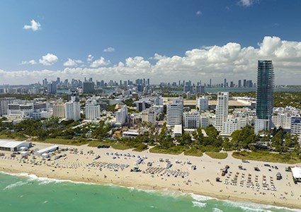 Aerial of Florida coastal cityscape with ocean and beach in foreground, hotels and condominiums behind