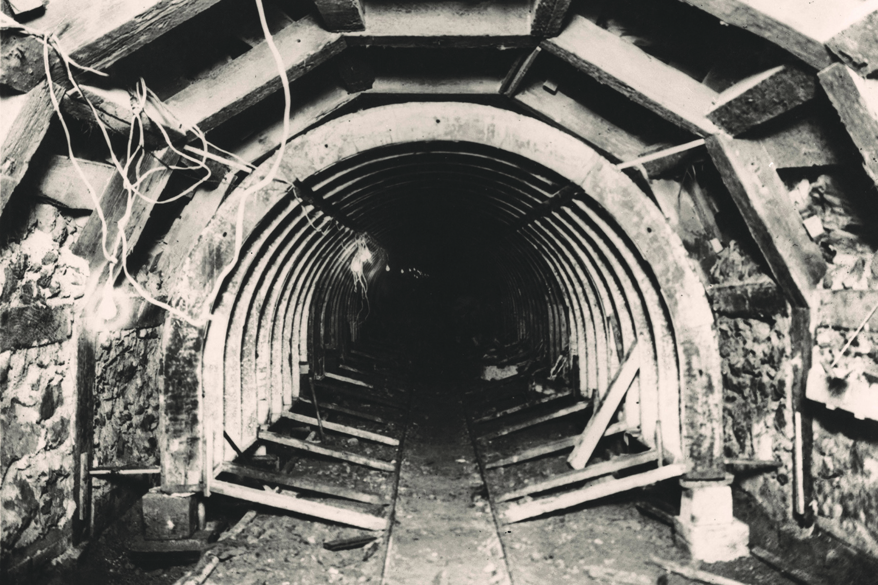 Sepia-toned photograph shows a tunnel being built with its timber supports. 