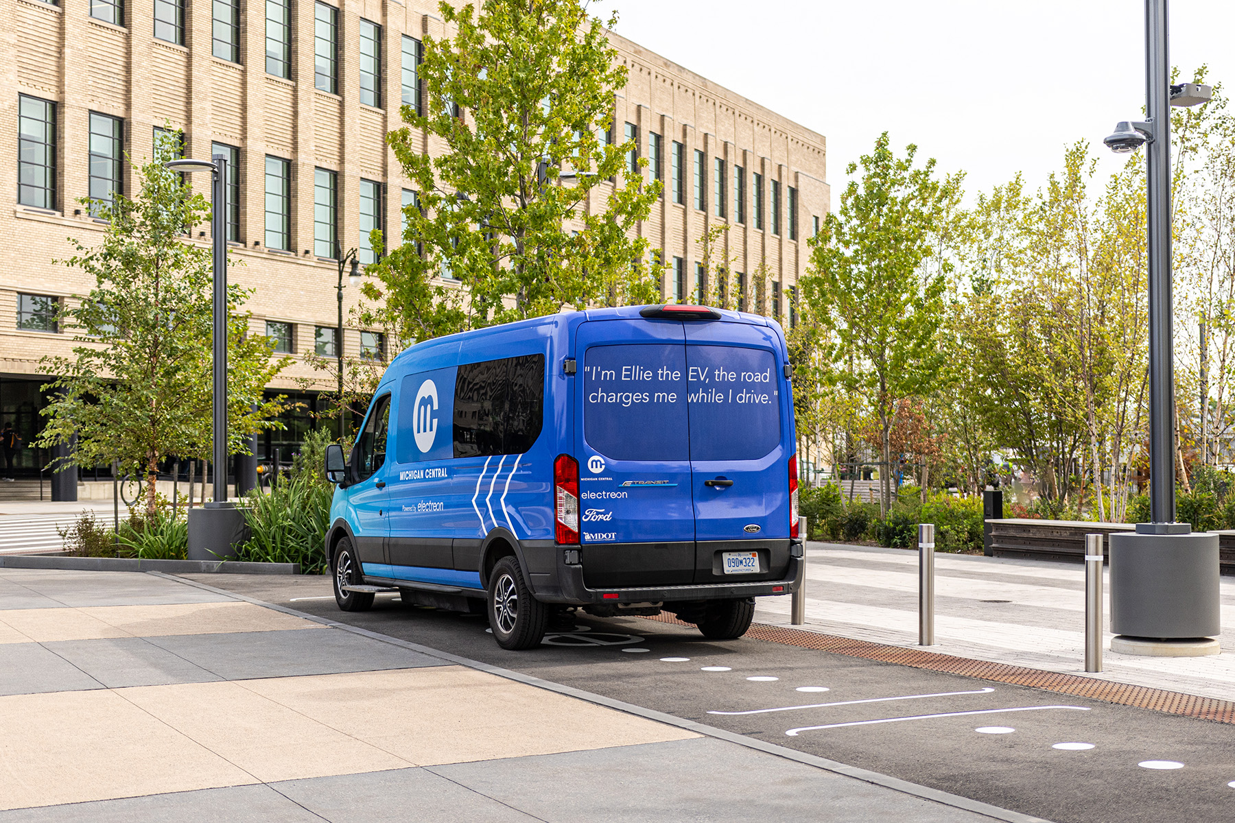 A blue van is shown atop a section of the street with an embedded charging system.