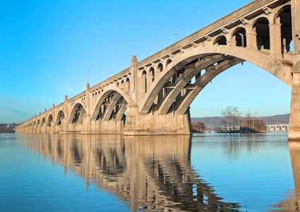 Photograph of a long concrete bridge over water that has many arches. 