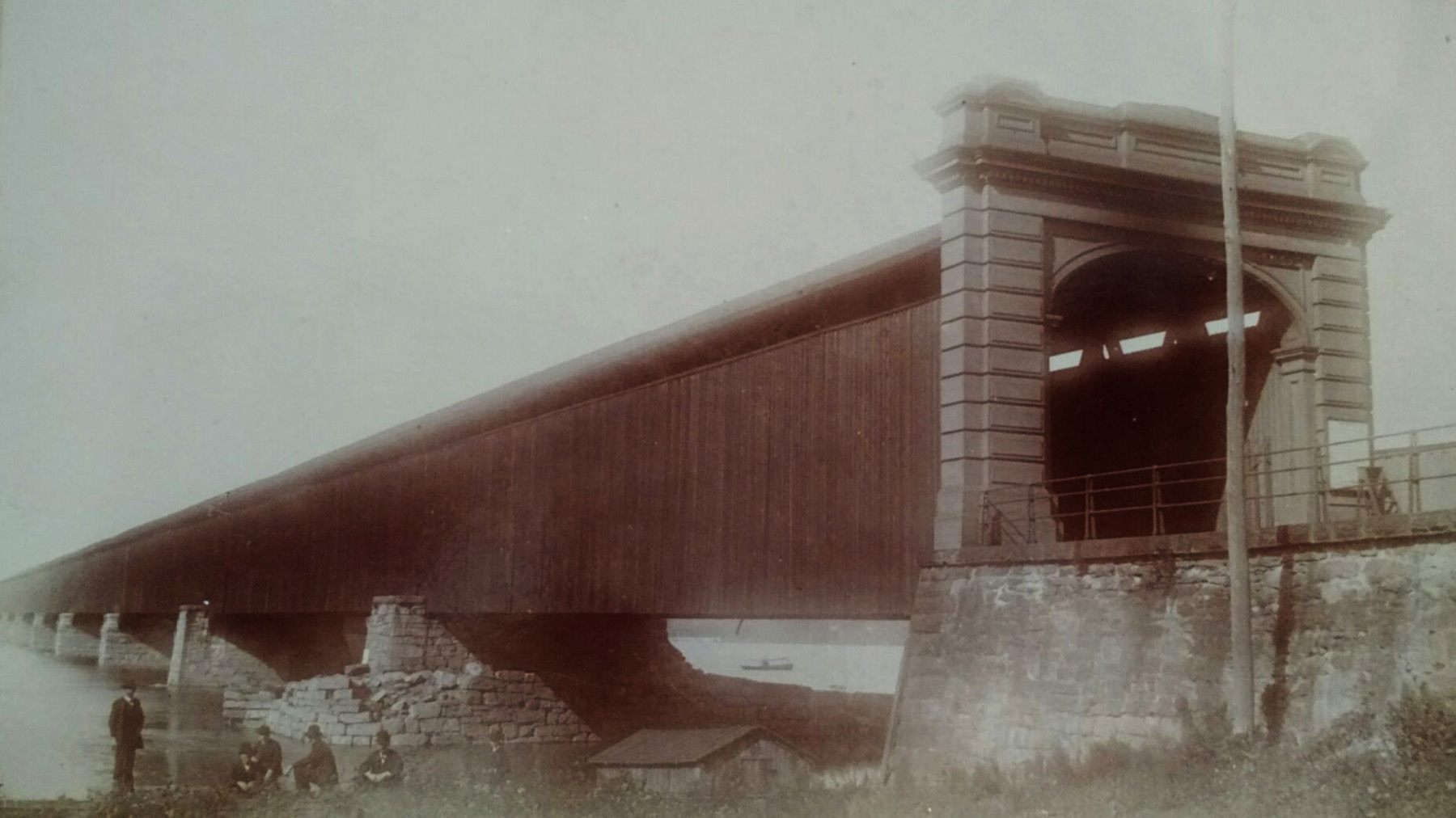 Black and white photo of a wooden covered bridge. 