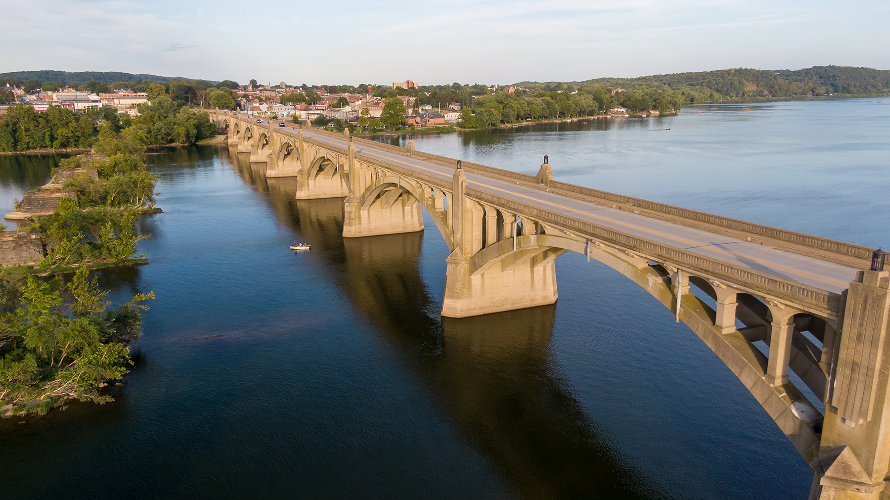 Photograph of a long concrete bridge over water that has many arches. 