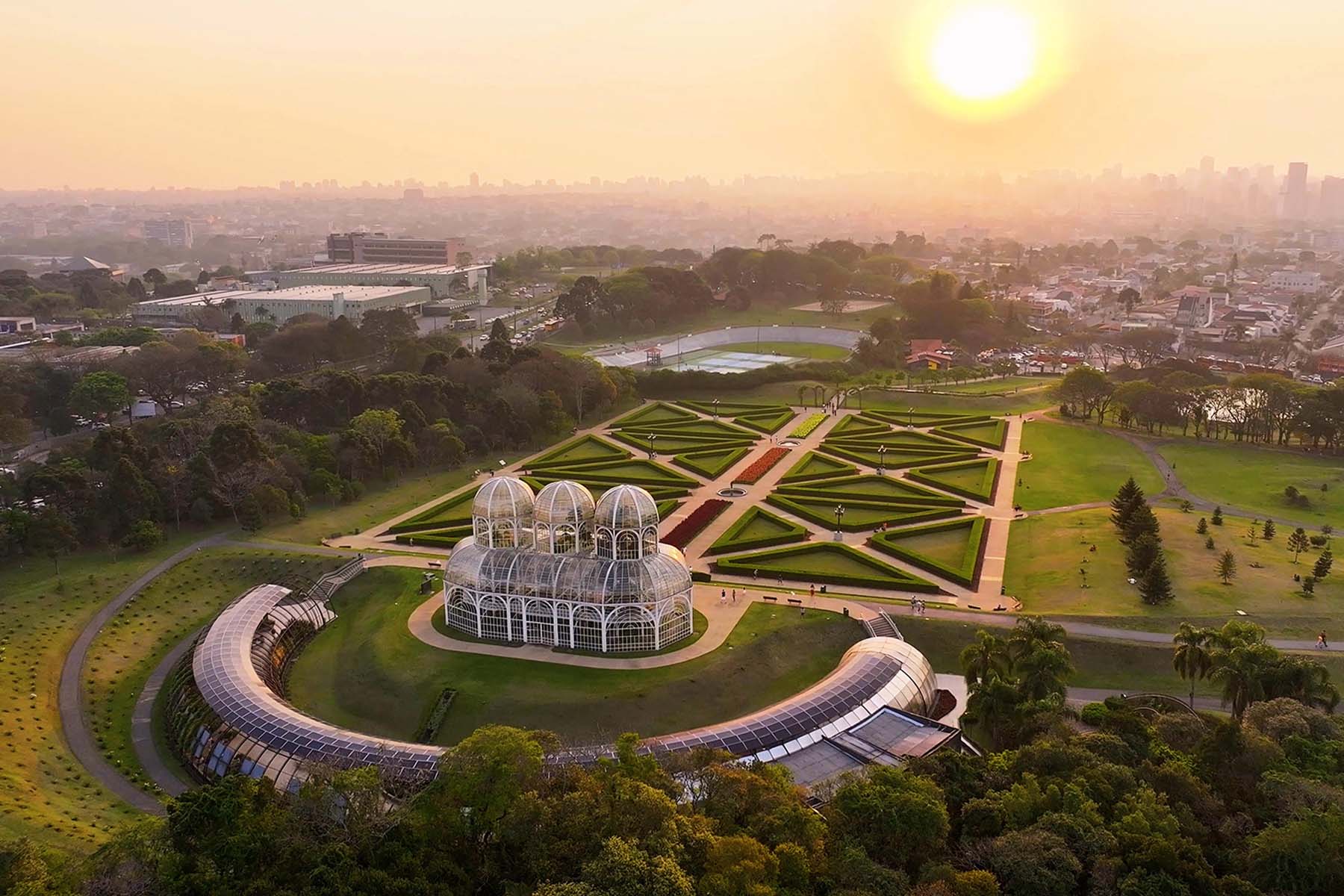 A large greenhouse is shown within a carefully planned park setting. 