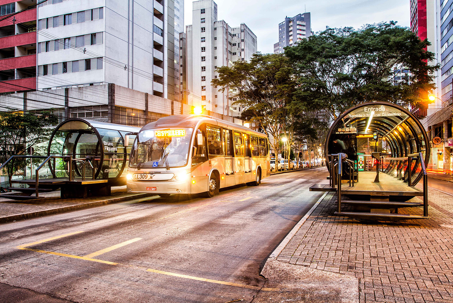 The glazed, tubular stations for Curitiba’s bus rapid transit system are depicted, with a bus stopped at one such station.