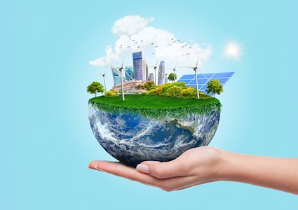 Image shows a woman’s hand holding half the earth. The top of the Earth is covered in green grass and plants. A cityscape with with windmills in the foreground and background can also be seen. 