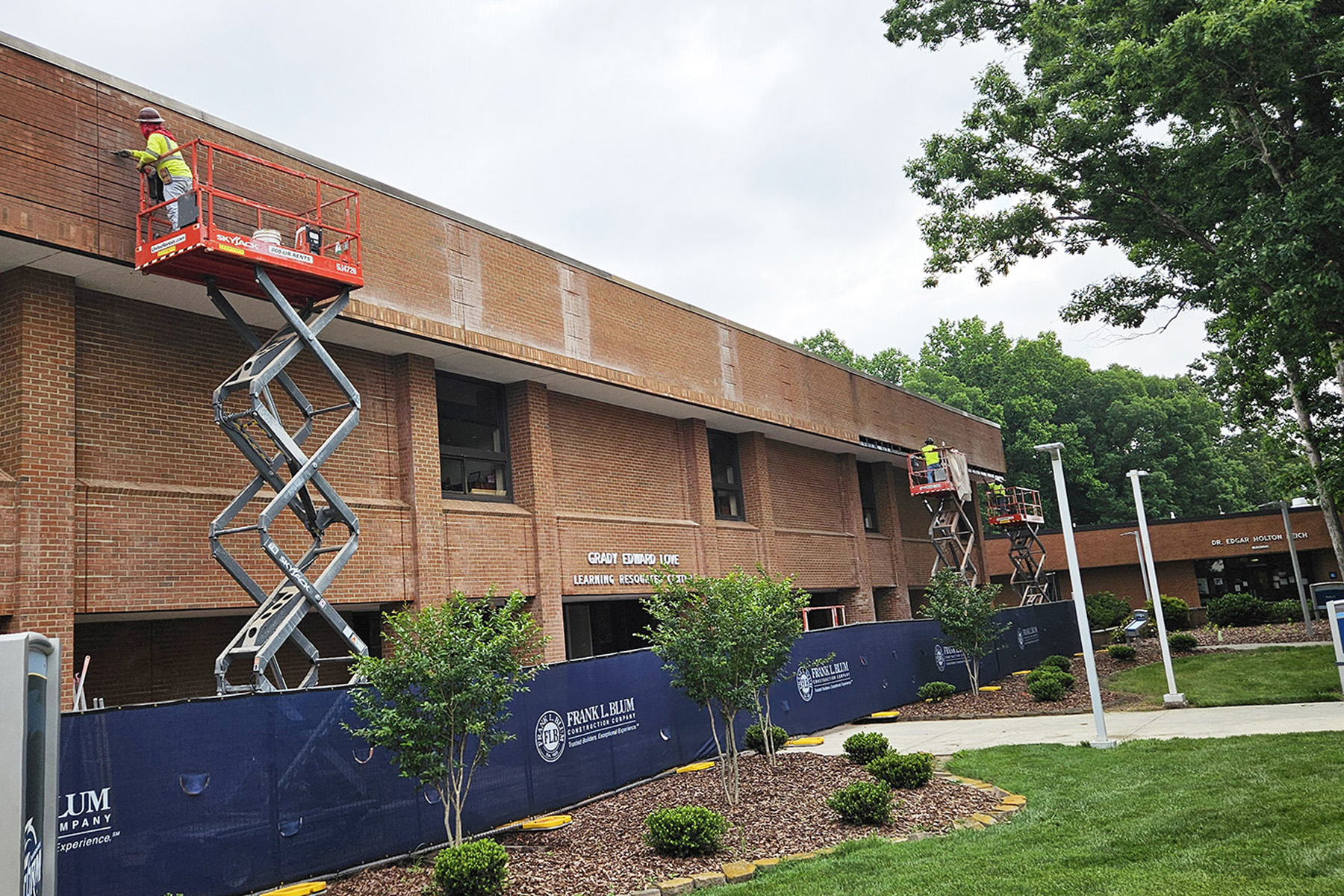 A scissor lift provides access to examine the brickwork of a community college building. 