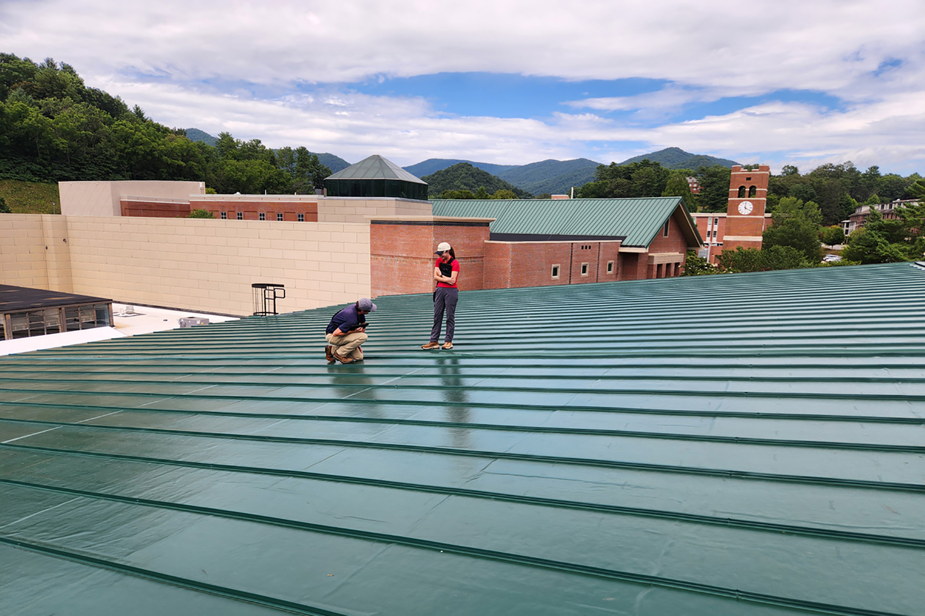 Two engineers are shown atop a sloping roof. 