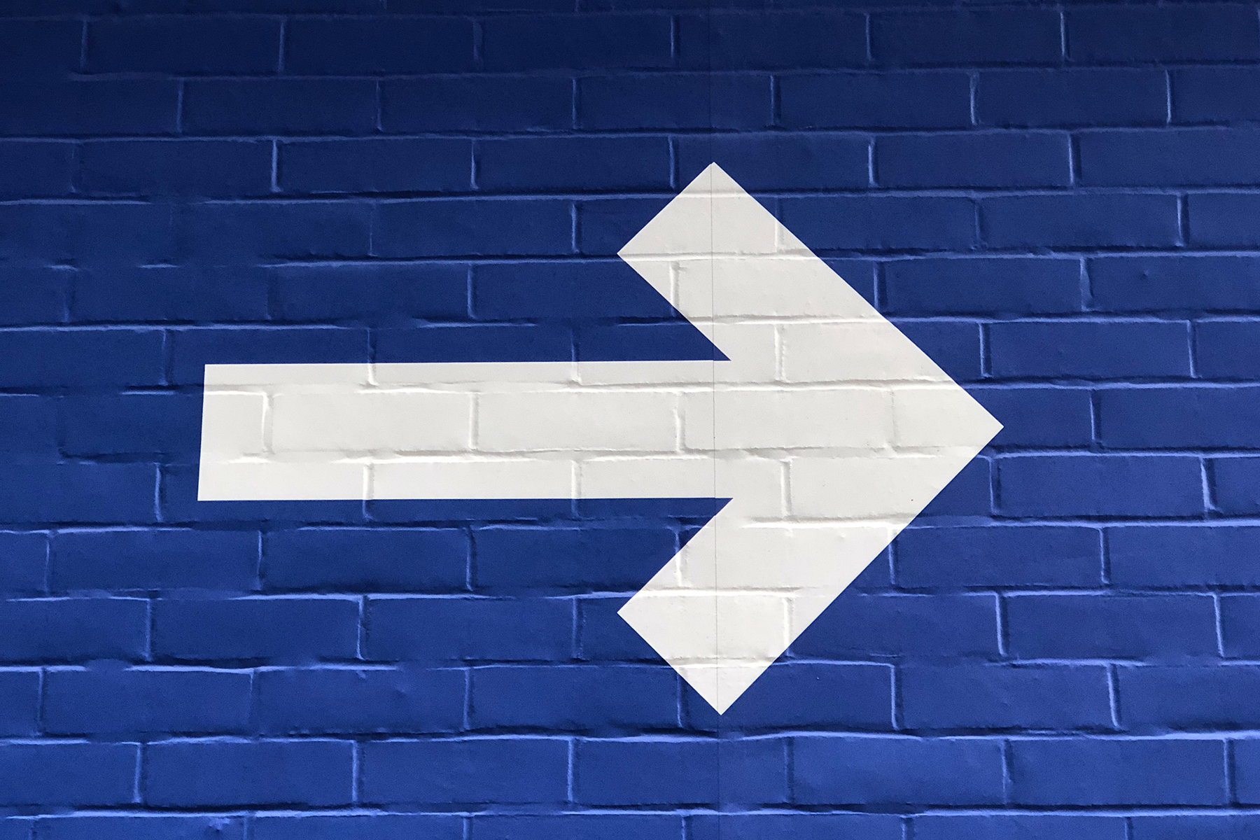 White arrow pointing right on a blue background.
