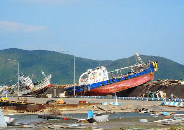 A tsunami caused a ferry to land on a pier. The pier is strewn with other debris as well.