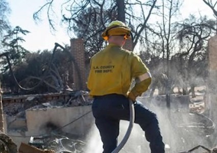 a firefighter sprays water on an affected area
