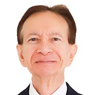 An adult man with hands crossed in front of him looks out at the camera. 