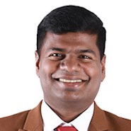 A man in a suit smiles at the camera. 